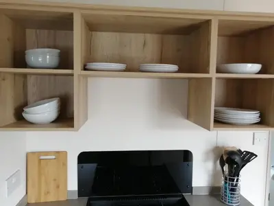 a kitchen with wooden cabinets with plates and bowls at 709 Seawick in Jaywick Sands