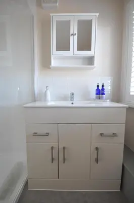 a bathroom with a white sink and a mirror at Corner Cottage in Cambridge