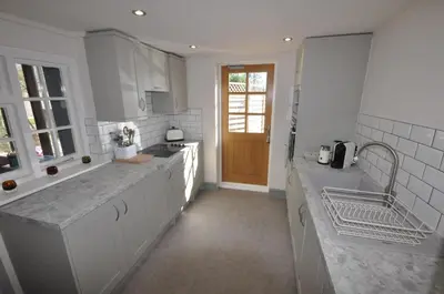 a kitchen with white cabinets and a sink and a counter at Corner Cottage in Cambridge