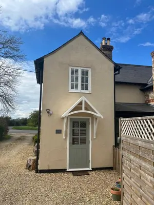 a house with a green door in a gravel driveway at Corner Cottage in Cambridge