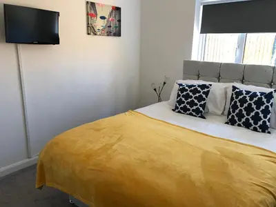 a bedroom with a bed with a yellow blanket at Stanford Villa in Stanford le Hope