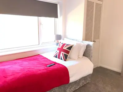a bedroom with a large bed with a red blanket at Stanford Villa in Stanford le Hope