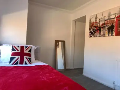 a bedroom with a bed with a red blanket at Stanford Villa in Stanford le Hope