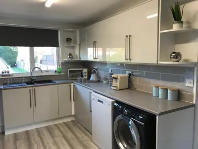 a kitchen with white cabinets and a washing machine at Stanford Villa in Stanford le Hope