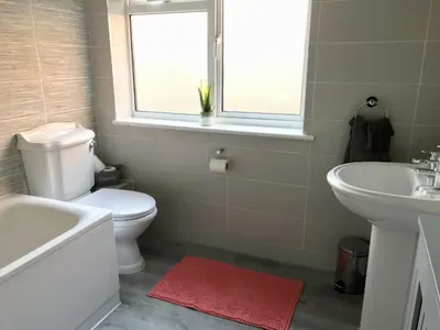 a bathroom with a toilet and a sink and a window at Stanford Villa in Stanford le Hope
