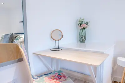 a white desk with a mirror and a vase of flowers at Lily Cottage, Leiston in Leiston