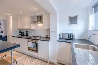 a kitchen with white cabinets and a counter top at Lily Cottage, Leiston in Leiston