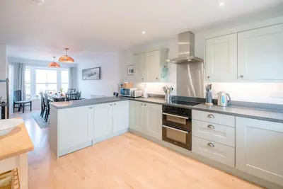 a kitchen with white cabinets and a counter top at Rest Ashored, Aldeburgh in Aldeburgh