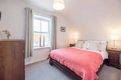 a bedroom with a bed with a red blanket and a window at Rest Ashored, Aldeburgh in Aldeburgh