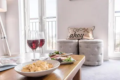 a table with a plate of food and a glass of wine at Rest Ashored, Aldeburgh in Aldeburgh