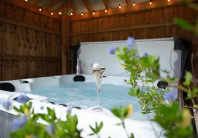 a bath tub with a glass of wine in it at City to Country Retreat Luxury Cottage with Hot Tub in Toppesfield