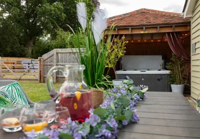 a table with a jug of tea and flowers on it at City to Country Retreat Luxury Cottage with Hot Tub in Toppesfield