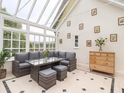a conservatory with a table and chairs in a room with windows at The Abbey Cottage in Cockfield