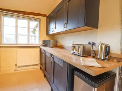 a kitchen with black cabinets and a wooden counter top at The Abbey Cottage in Cockfield