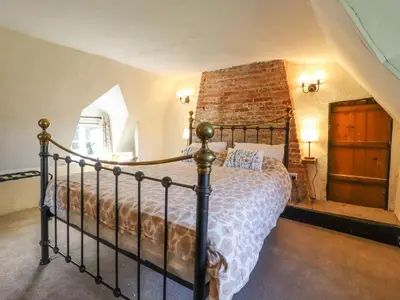 a bedroom with a bed and a brick wall at The Abbey Cottage in Cockfield