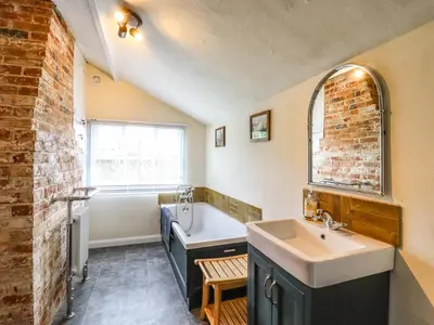 a bathroom with a sink and a bath tub and a bath tub at The Abbey Cottage in Cockfield