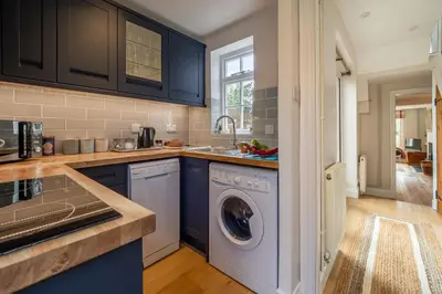 a kitchen with blue cabinets and a washing machine at Adorable cottage with a log burner in heavenly village - Constable Lodge in Nayland