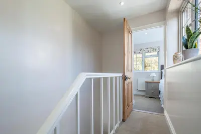 a hallway with a staircase with a door and a window at Adorable cottage with a log burner in heavenly village - Constable Lodge in Nayland