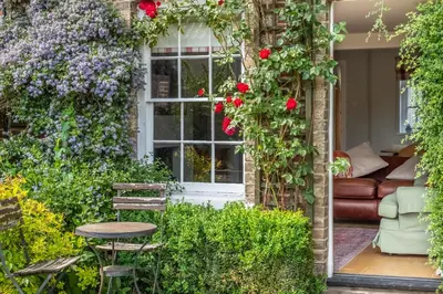 a garden with roses and a table and a window at Adorable cottage with a log burner in heavenly village - Constable Lodge in Nayland