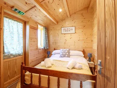 a bedroom with a bed in a log cabin at Clover Lodge in Leiston