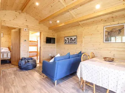 a living room with a blue couch and a table at Clover Lodge in Leiston