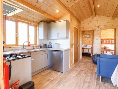 a kitchen in a log cabin with a stove at Clover Lodge in Leiston