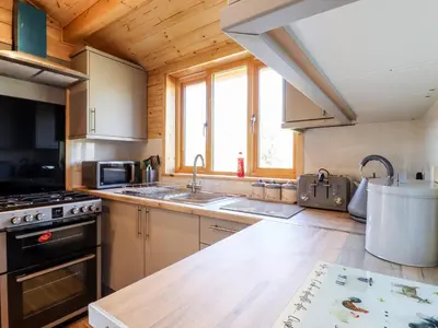 a kitchen with wooden cabinets and a stove top oven at Clover Lodge in Leiston