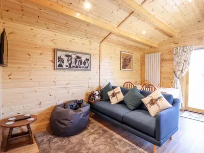 a living room with a blue couch and a table at Clover Lodge in Leiston