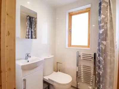 a bathroom with a toilet and a sink and a window at Clover Lodge in Leiston