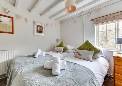 two beds in a room with white walls and windows at Appletree Cottage in Westleton