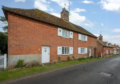 a red brick house with white windows and a street at Appletree Cottage in Westleton
