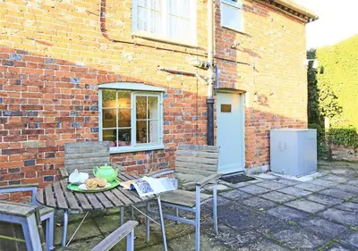 a table and chairs in front of a brick building at Appletree Cottage in Westleton