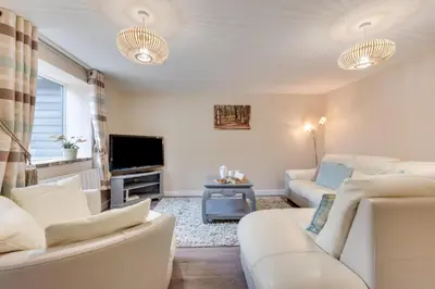 a living room with white furniture and a flat screen tv at 6 Bed in Great Waldingfield oc-ac4 in Great Waldingfield