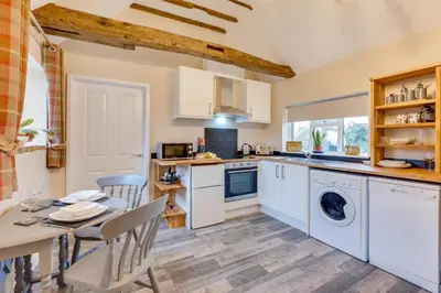 a kitchen with white cabinets and a table and chairs at 1 Bed in Great Waldingfield oc-ac1 in Great Waldingfield