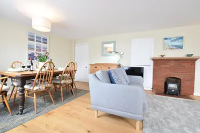 a living room with a dining room table and a fireplace at Seaflower, Aldeburgh in Aldeburgh