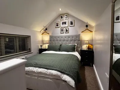 a bedroom with a bed with a green comforter at The Tower, 1 bed 1850's Tiny House in Maldon