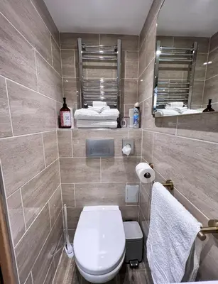 a bathroom with a toilet and a mirror and towels at The Tower, 1 bed 1850's Tiny House in Maldon