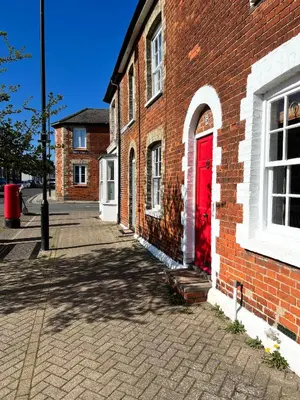 a brick building with a red door on a street at The Tower, 1 bed 1850's Tiny House in Maldon