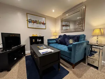 a living room with a blue couch and a tv at The Tower, 1 bed 1850's Tiny House in Maldon
