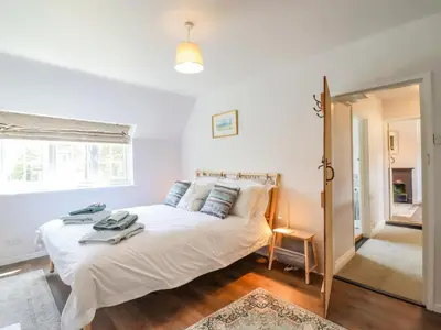 a bedroom with a large white bed and a window at Bluebird Cottage in Higham