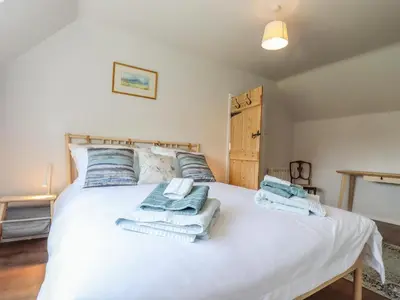 a bedroom with a white bed with towels on it at Bluebird Cottage in Higham