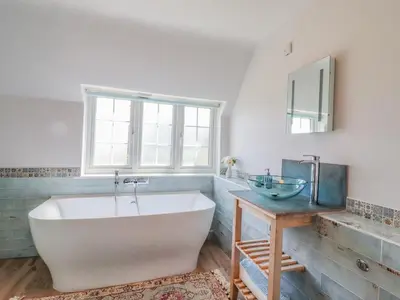 a bathroom with a large white tub and a sink at Bluebird Cottage in Higham