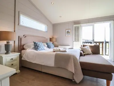 a bedroom with a large bed and a chair at Skylarks in Hengrave
