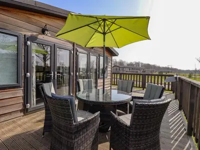 a patio with a table and chairs and an umbrella at Skylarks in Hengrave