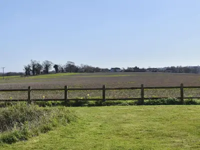 a wooden fence in front of a field at The Stables in Bealings