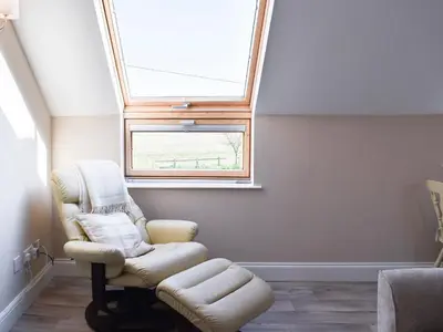 a living room with a skylight and a chair at The Stables in Bealings