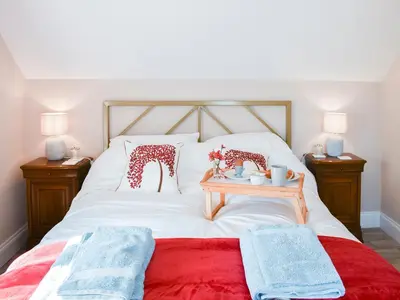 a white bed with two pillows and a table on it at The Stables in Bealings