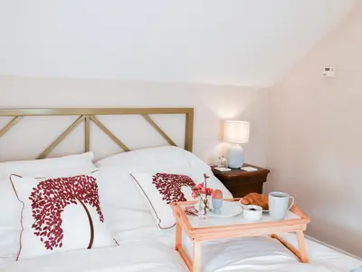 a bed with white sheets and pillows with a wooden table at The Stables in Bealings