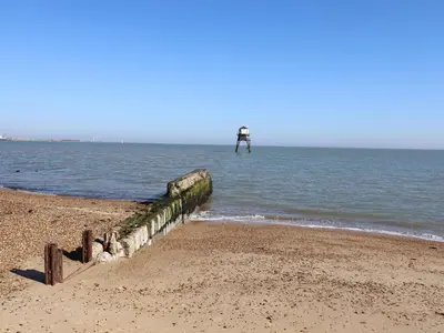 a pier on the beach with a lighthouse in the water at Flat 19 By The Beach in Harwich