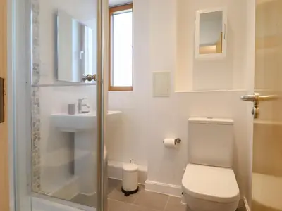 a white bathroom with a toilet and a sink at Flat 19 By The Beach in Harwich